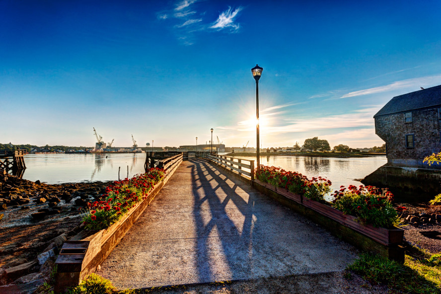 A bridge spans over calm water, connecting two landmasses under a clear blue sky
